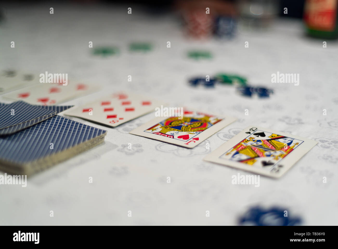 Poker Gemeinschaftskarten aufgedeckt und Chips wie Wetten auf einen Tisch mit weißer Tischdecke platziert. Stockfoto