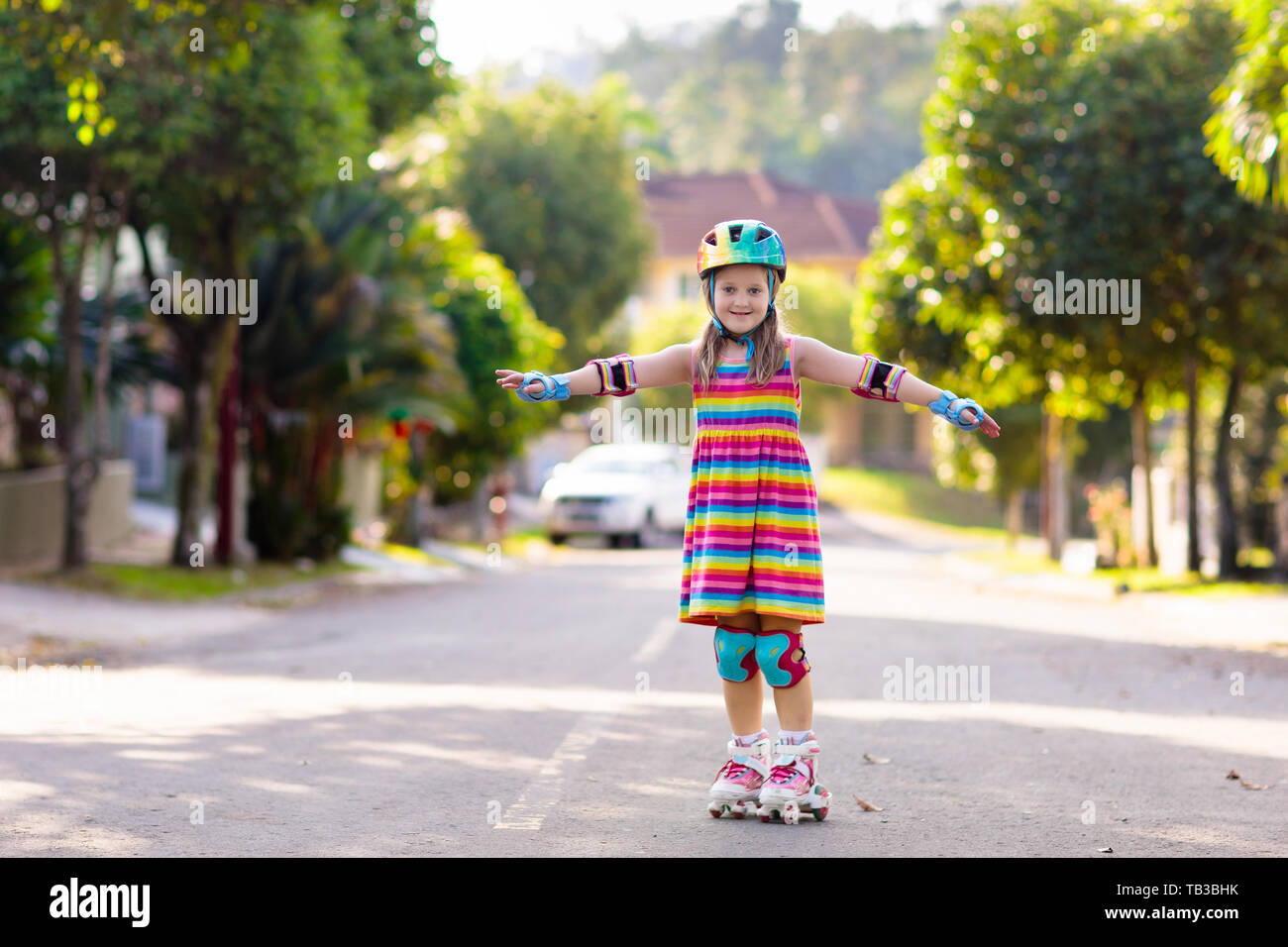 Kind auf Inline Skates in Park. Kinder lernen roller blades zu skaten. Kleines Mädchen skaten am sonnigen Sommertag. Aktivität im Freien für Kinder zum sicheren Resi Stockfoto