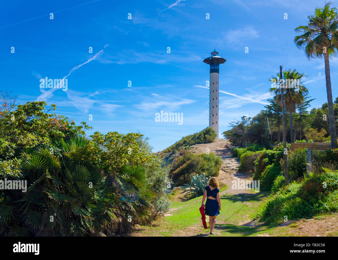 Frau im blauen Kleid zu Fuß auf den Weg, der zu Torredembarra Leuchtturm führt Stockfoto