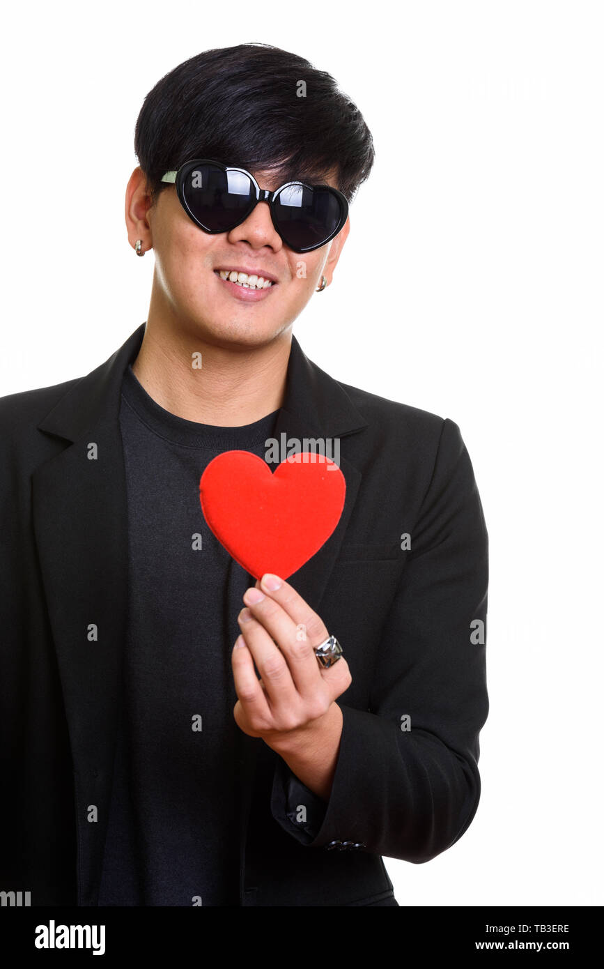 Cool happy asiatischer Mann lächelnd, während tragende herzförmige Sunglass Stockfoto