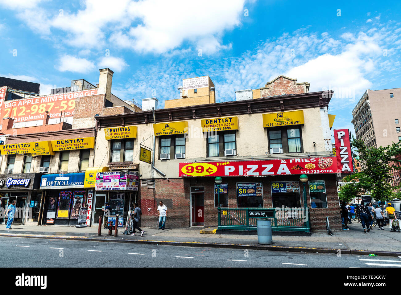 New York City, USA - 31. Juli 2018: Geschäfte, Apotheke, Zahnarzt, Lebensmittelgeschäft, Pizzeria und der U-Bahn station mit Menschen in Harlem, New York City, USA Stockfoto