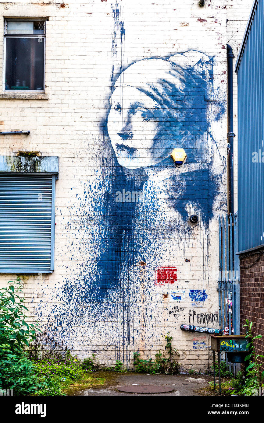 Street Art Graffiti von Banksy' Mädchen mit dem Durchbohrten Trommelfell' mit einer Farbe spritzen in Albion Docks, Bristol, UK geschaendet Stockfoto