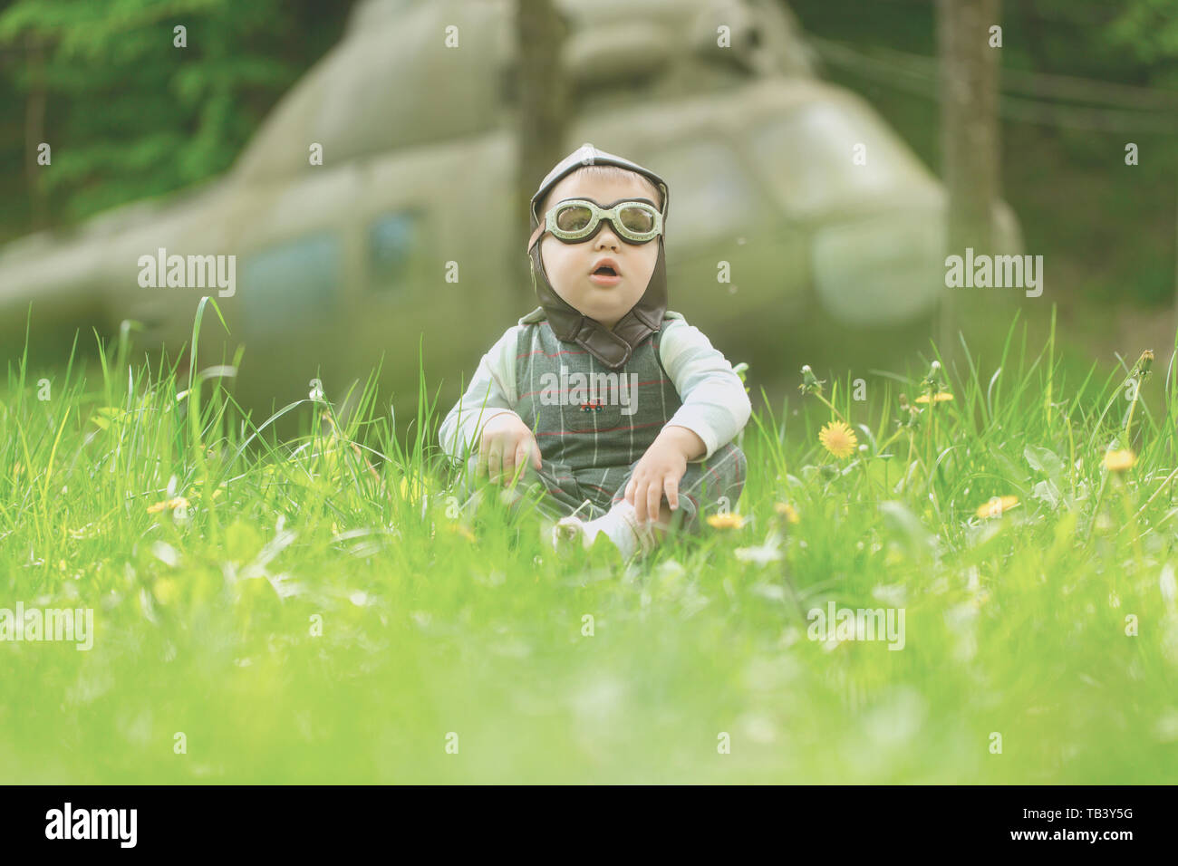 Junge in Pilot Helm und Brille in grün Gras sitzen Stockfotografie Alamy