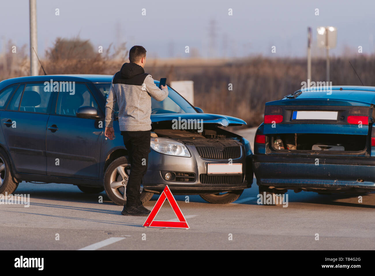 Ein Mann mit einem Smart Phone ein Foto von den Schaden an seinem Auto durch einen Autounfall verursacht zu nehmen Stockfoto
