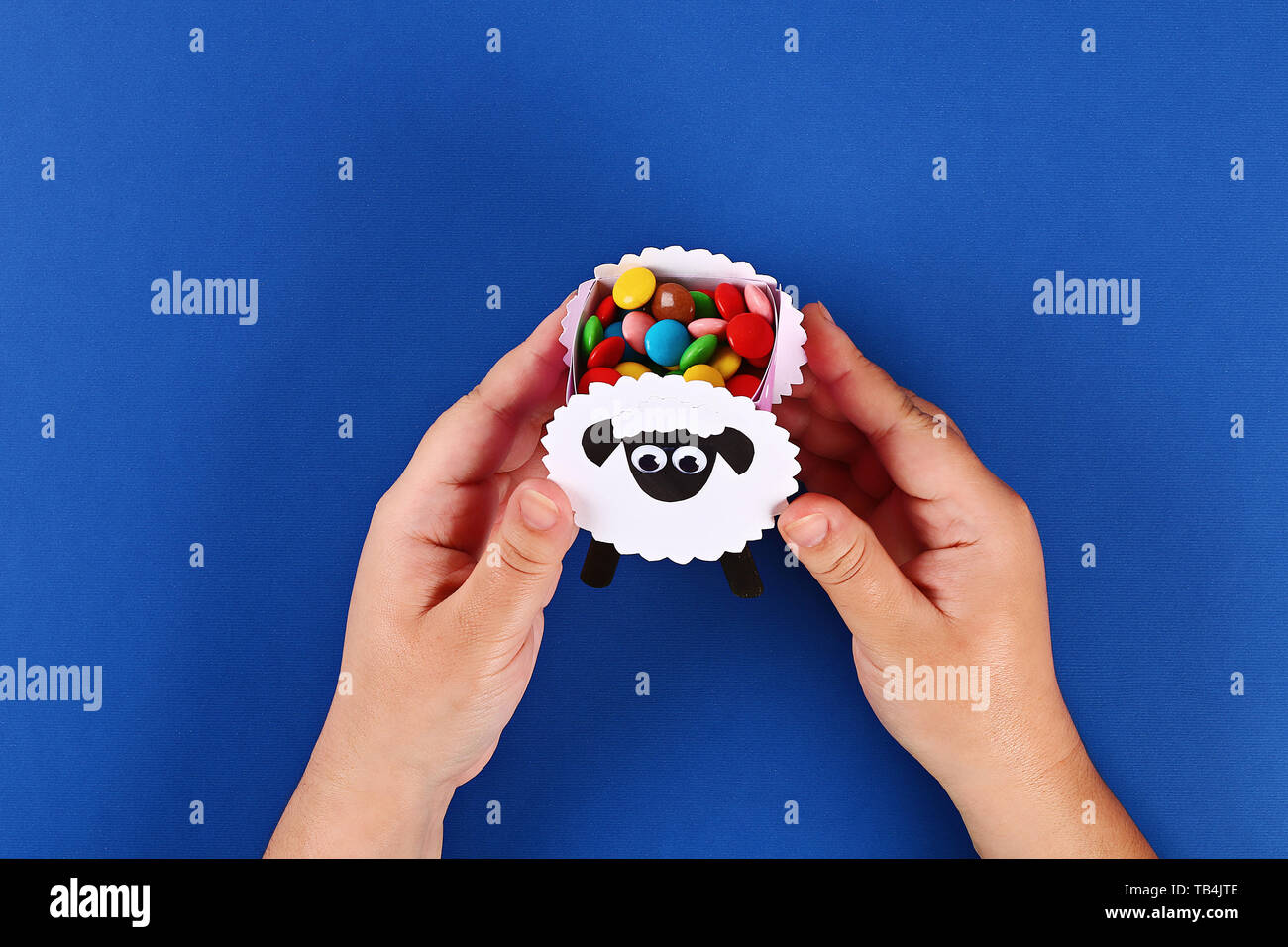 24 DIY-Eid Al Adha Lamm Schafe Süßigkeiten Papier, Holzstäbchen für Speiseeis auf blauem Hintergrund. Geschenk Idee, Dekor Eid Al Adha. Schritt für Schritt. Ansicht von oben. Stockfoto