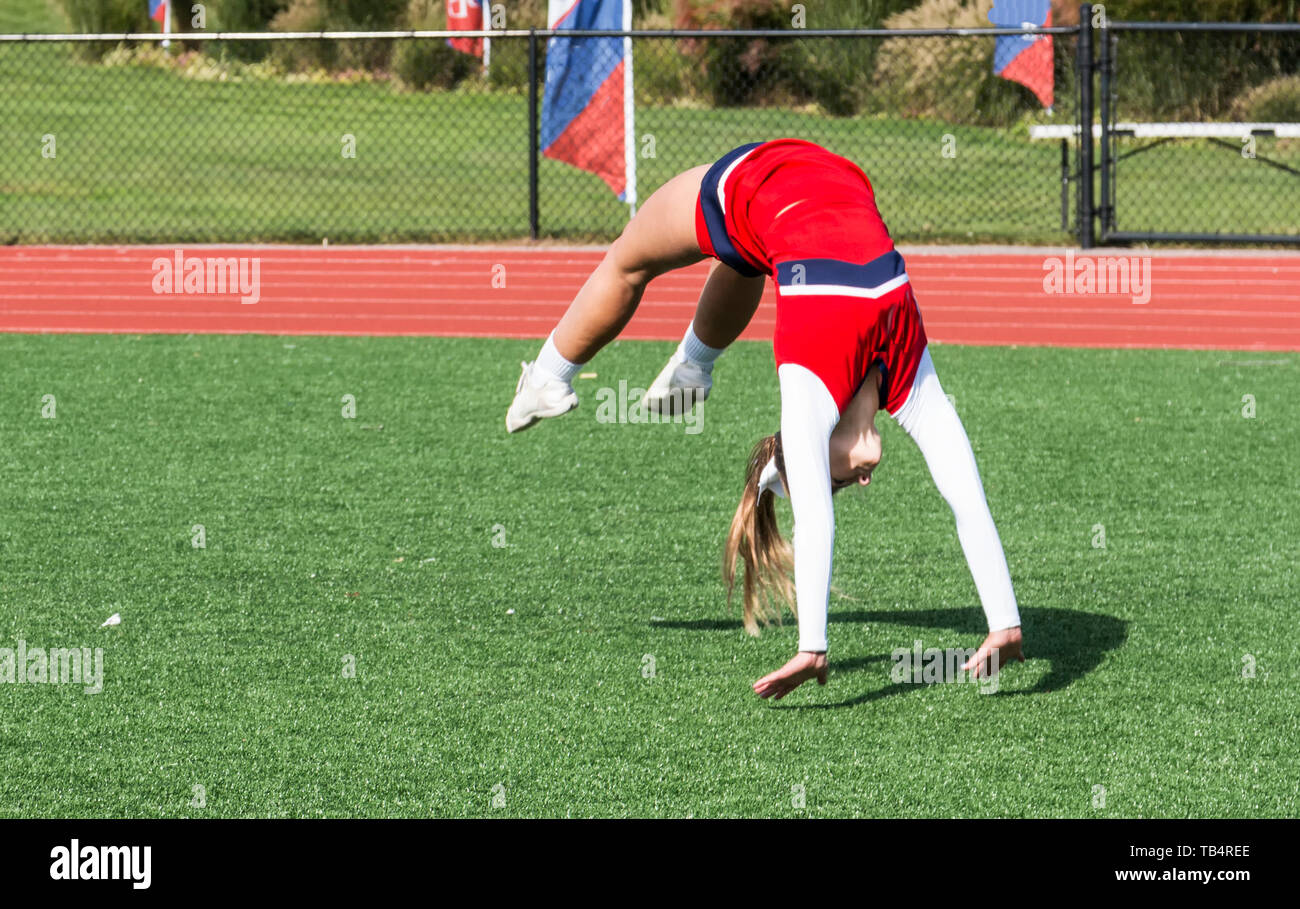 Eine High School Cheerleader üben klappt auf dem Rasen vor einem Fußballspiel. Stockfoto