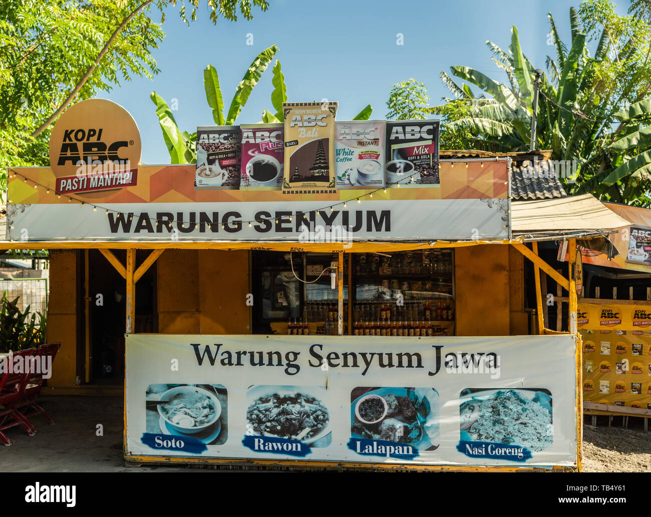 Denpasar, Bali, Indonesien - 26. Februar 2019: Kleine Kaffee shopt anzeigen Bilder von Kaffee gegen Gelb zurück und Unter grünem Laub und blauer Sk Stockfoto