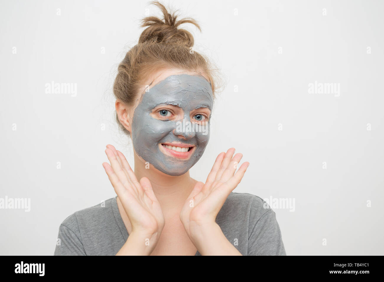 Junge kaukasier Frau mit schwarzen oder grauen Gesichtsbehandlung Clay Mask auf ihrem Gesicht, ein Lächeln auf den Lippen Stockfoto