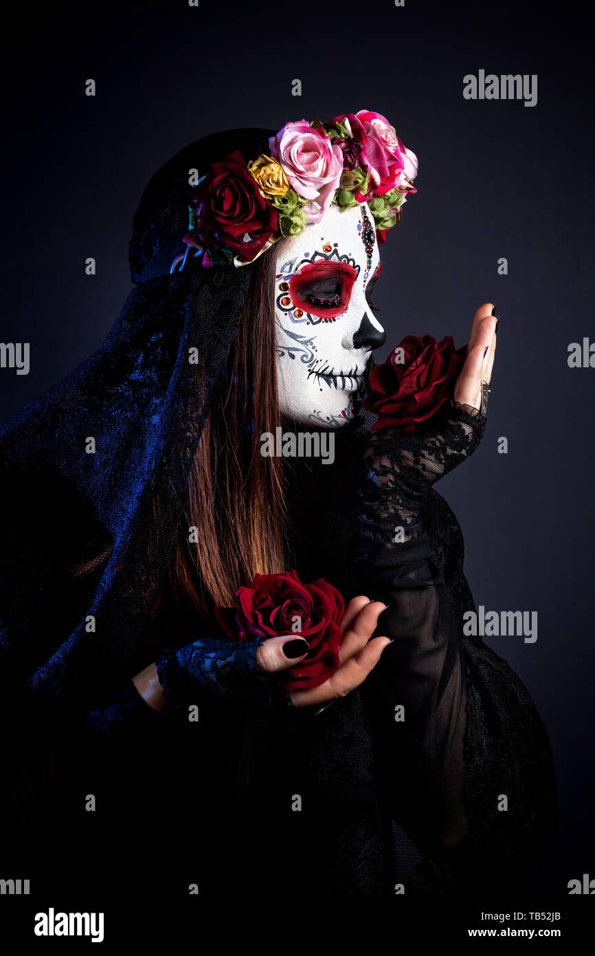 Mädchen mit Sugar Skull mit rosa Blüten feiert Tag der Toten auf schwarzen Hintergrund machen Stockfoto