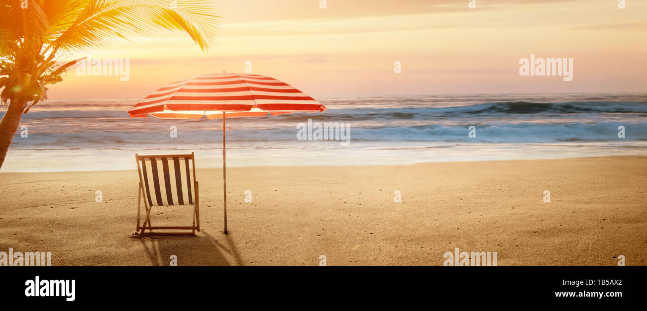 Tropischen Strand im Sonnenuntergang mit Liegestuhl und Sonnenschirm Stockfoto