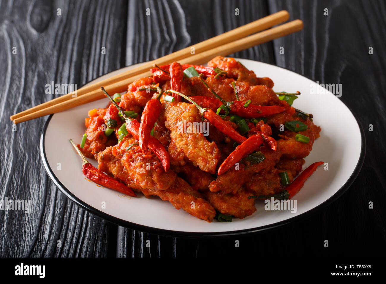 Traditionelle spicy szechuan Huhn in Soße Schezwan close-up auf einem Teller auf den Tisch. Horizontale Stockfoto