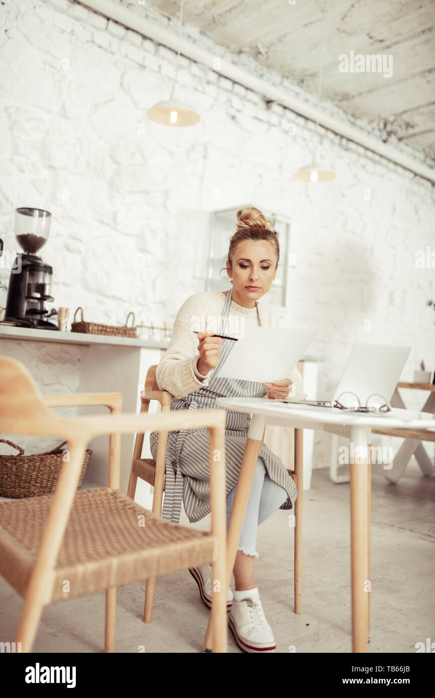 Zählen von Einkommen. Smart Besitzer einer Coffee Shop am Tisch sitzen in ihrem Café und Arbeiten. Stockfoto