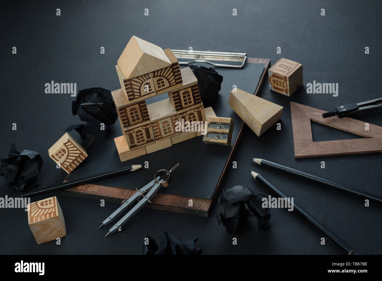 Bau ein Haus, Immobilien Planung und Studium der Architektur Konzept. Dark Header mit Spielzeug Holzklötze, kleines Haus, Bleistifte und Kopieren. Stockfoto