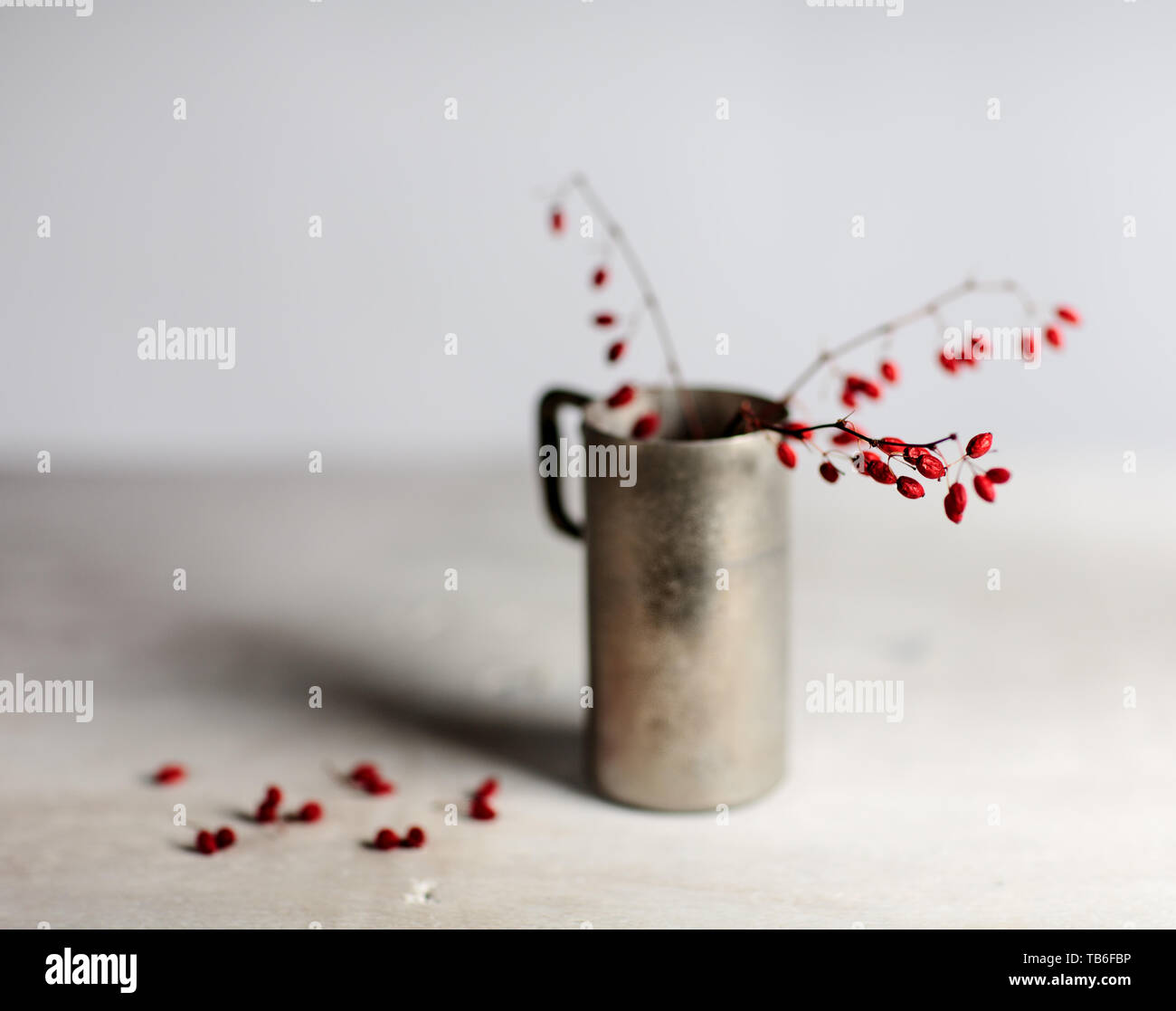 Stillleben mit roten Beeren im Metall kann auf Holzbrett Stockfoto