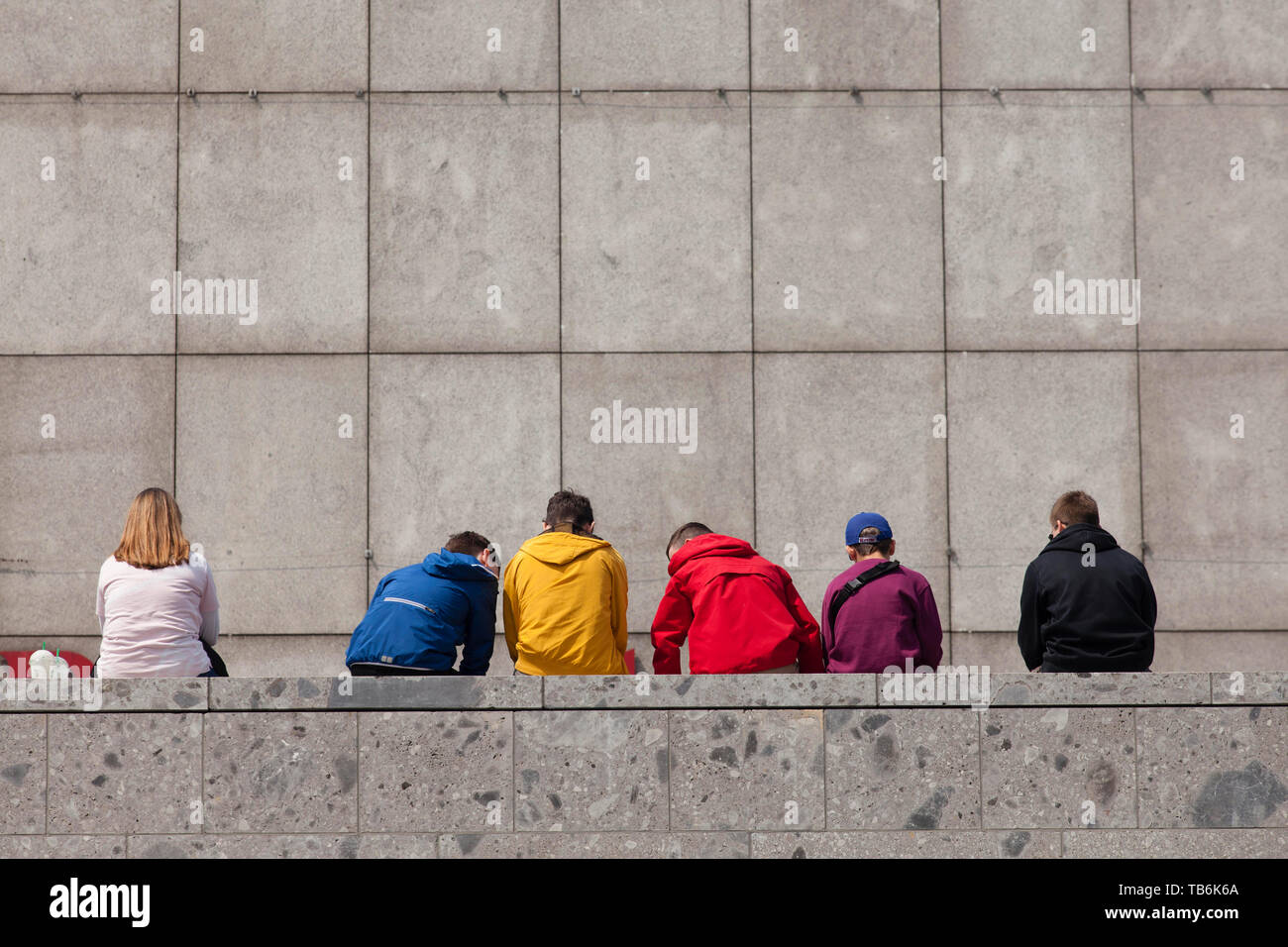Junge Menschen auf eine Wand an der Römisch-germanisches Museum, Köln, Deutschland sitzen. Jugendliche Artikel in einer Mauer bin Roemisch-Germanischen Museum, Ko Stockfoto