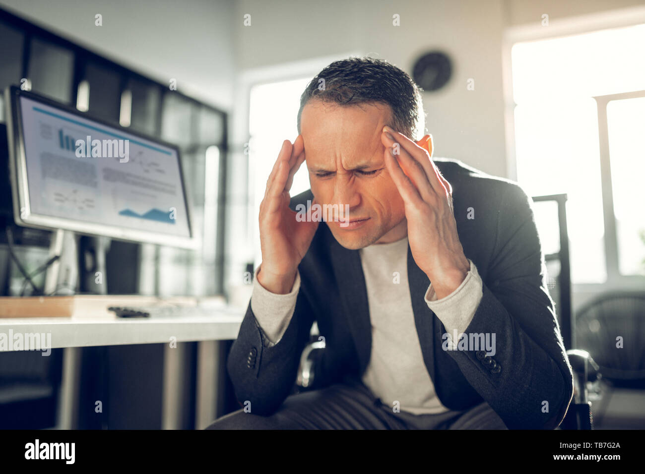 Dunkelhaarige Geschäftsmann Gefühl schrecklich leiden unter Kopfschmerzen. Stockfoto