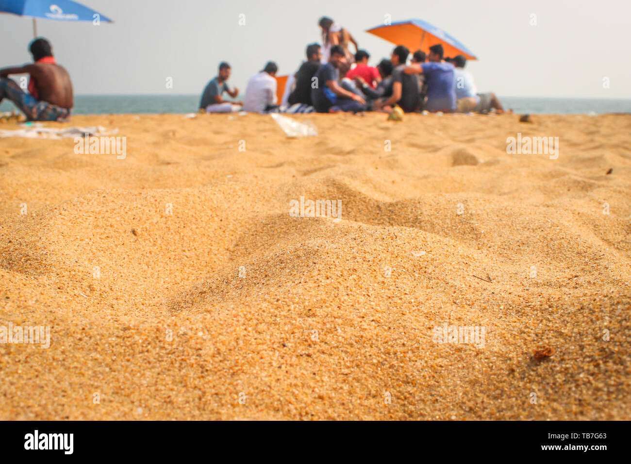 Eine Gruppe von Menschen genießen die Sonne am Strand von Goa. Menschen mit Sonnenschirmen am Strand. Stockfoto