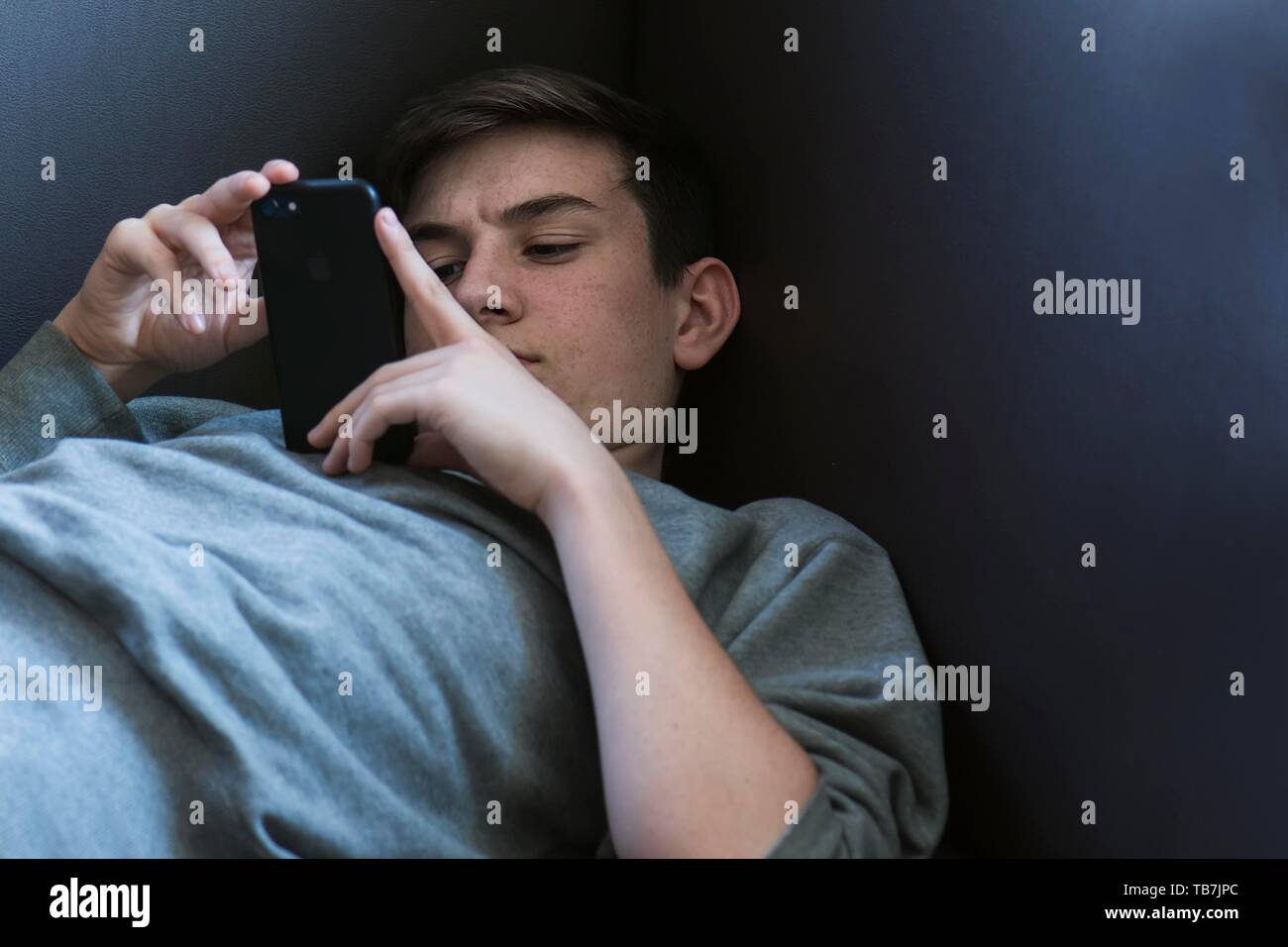 Teenager 15 Jahre, liegen auf dem Sofa und sein iPhone, Baden-Württemberg, Deutschland spielen Stockfoto