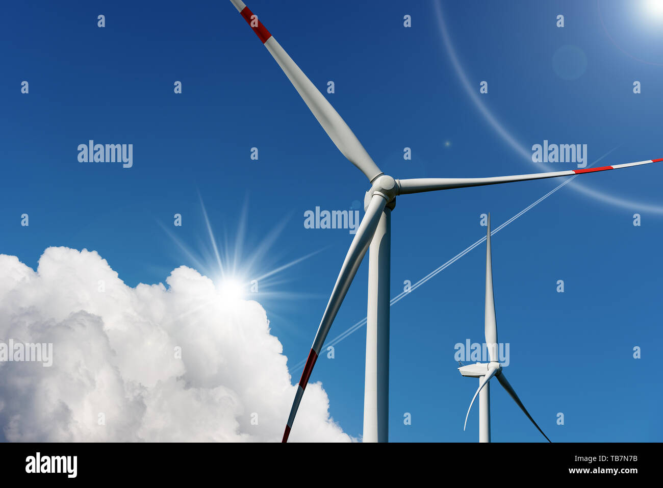 Zwei Windenergieanlagen auf einen blauen Himmel mit Wolken und Sonnenstrahlen - Erneuerbare Energie Konzept Stockfoto