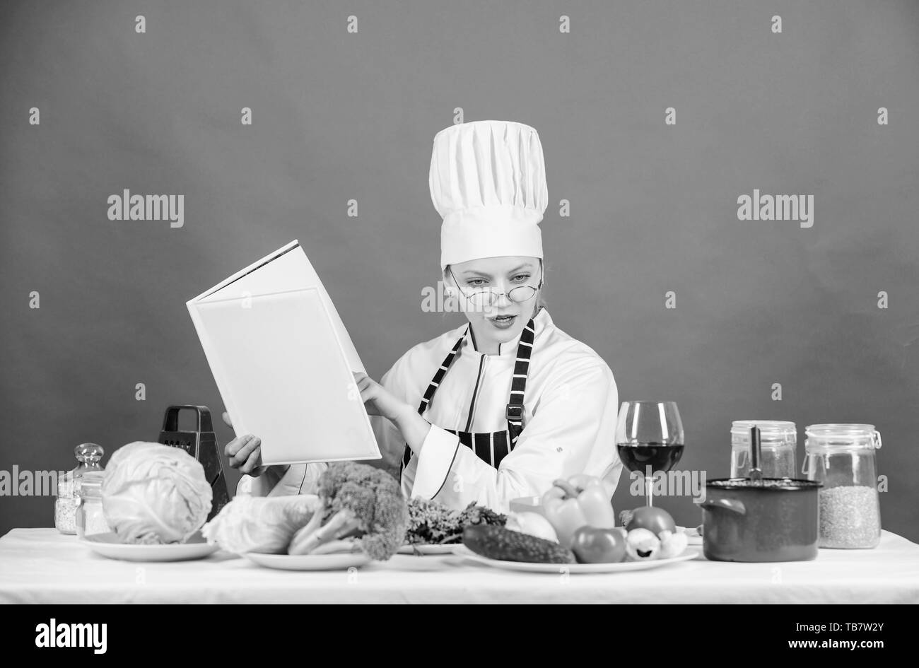 Kulinarische Ausbildung Konzept. Weibliche in Hut und Schürze weiß alles über kulinarische Künste kochen Skill verbessern. Kulinarische Experte. Frau Koch Kochen gesund essen. Mädchen Buch lesen beste Kulinarische Rezepte. Stockfoto