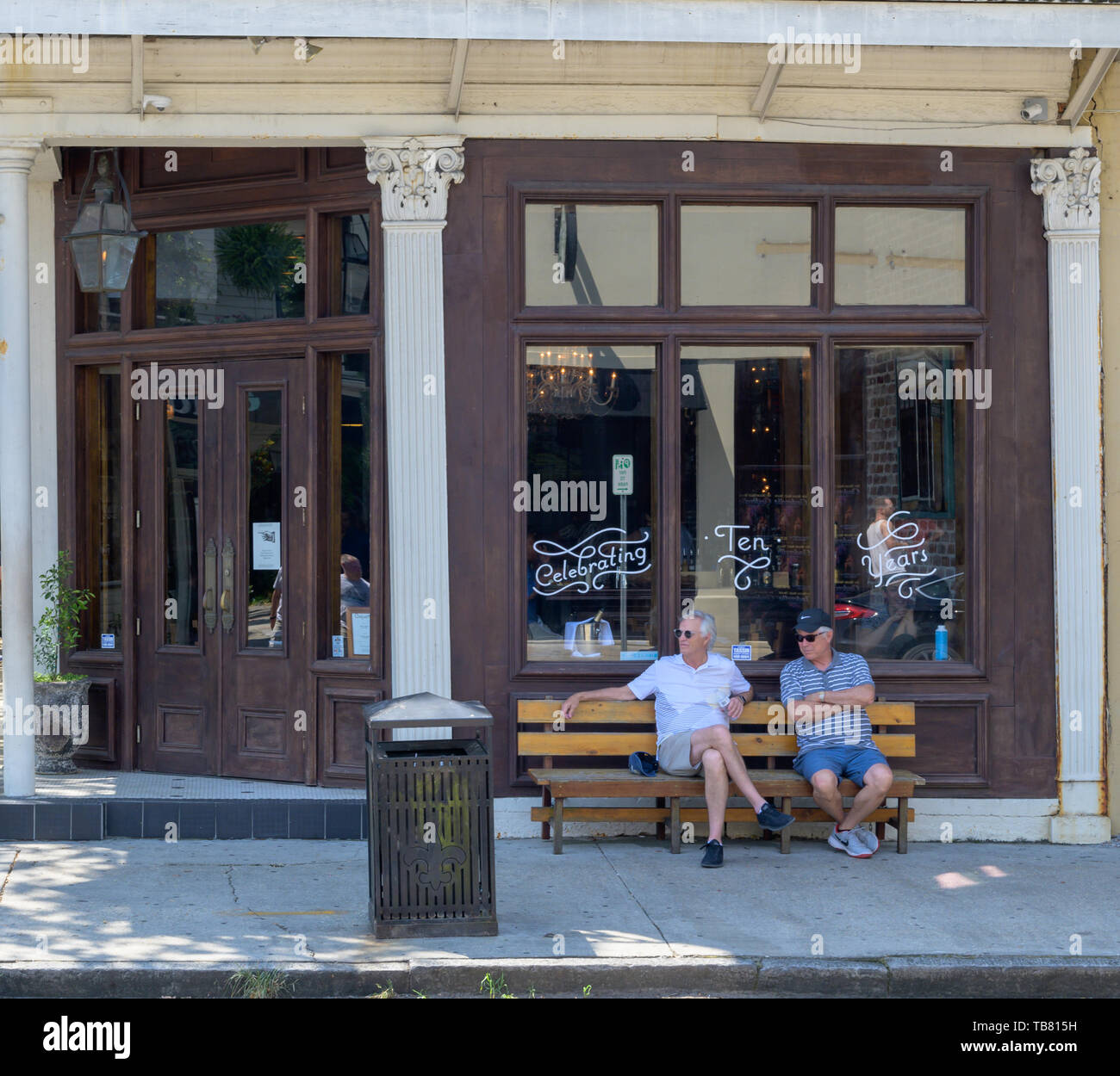 New Orleans, LA, USA - 26. Mai 2019. Zwei Männer sitzen auf einer Bank und außerhalb ein Restaurant in New Orleans entspannen. Stockfoto