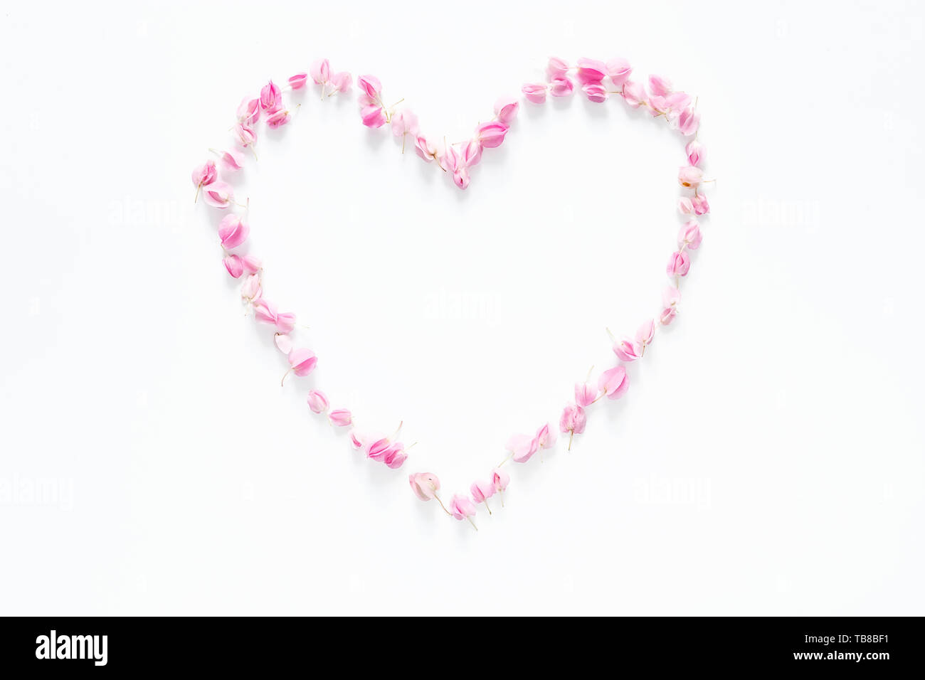 Flach von floralen Herz aus Blüten Rosa auf weißem Hintergrund, Ansicht von oben. Blüte kreative Zusammensetzung Stockfoto