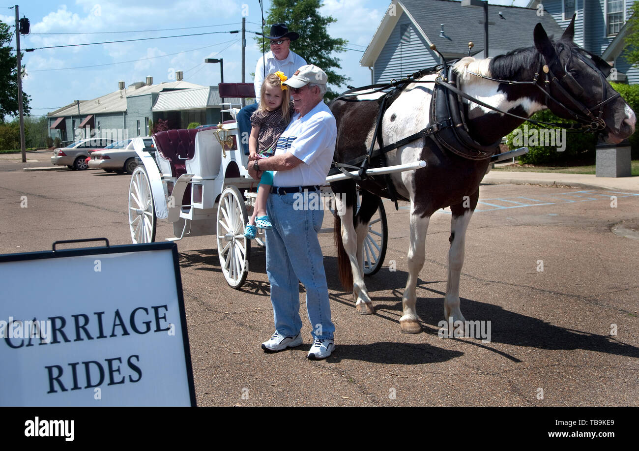 Ein Mann hält seine Enkelin, wie sie für ein Pferd warten - Kutschfahrt in Columbus, Mississippi. Stockfoto