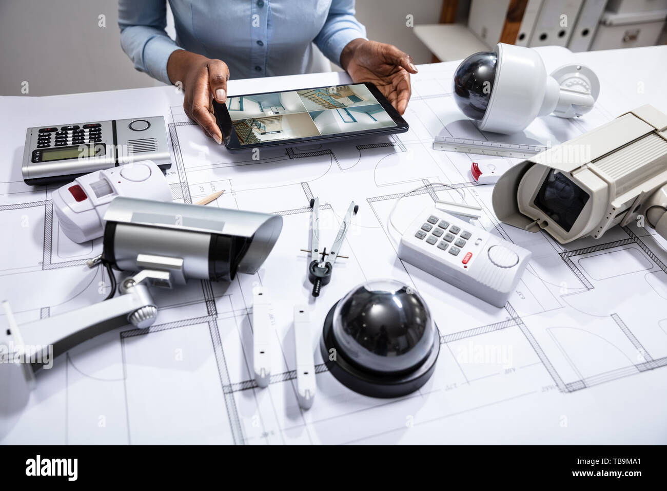 Einen erhöhten Blick auf die Person, die die Aufnahmen auf Digital Tablet mit Ausrüstungsgegenstände für die Gefahrenabwehr auf dem Bauplan Stockfoto