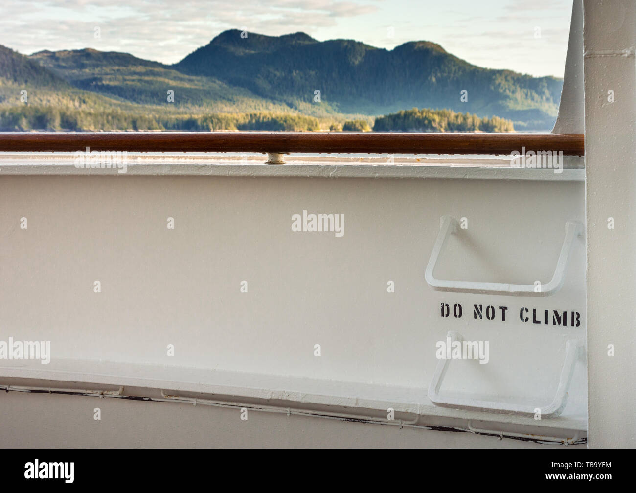 Metall Leitersprossen auf Kreuzfahrtschiff deck mit den Worten "Nicht klettern, und Blick auf die Bergkulisse im Hintergrund, Inside Passage, in der Nähe der Ketchikan, Alaska. Stockfoto