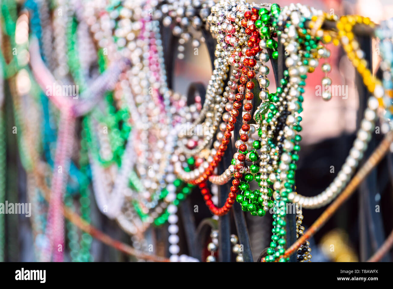 New Orleans, USA closeup von bunten Mardi Gras Perlen am Zaun durch farbenfrohe Gebäude Haus und niemand auf Bürgersteig Stockfoto