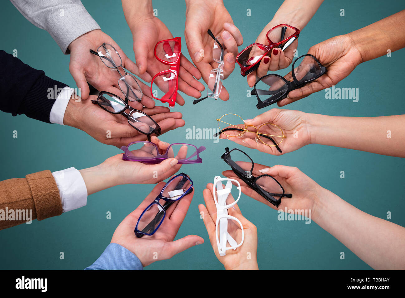 Blick von oben auf die Menschen an der Hand, die Vielzahl von Brillen gegen grüne Kulisse Stockfoto