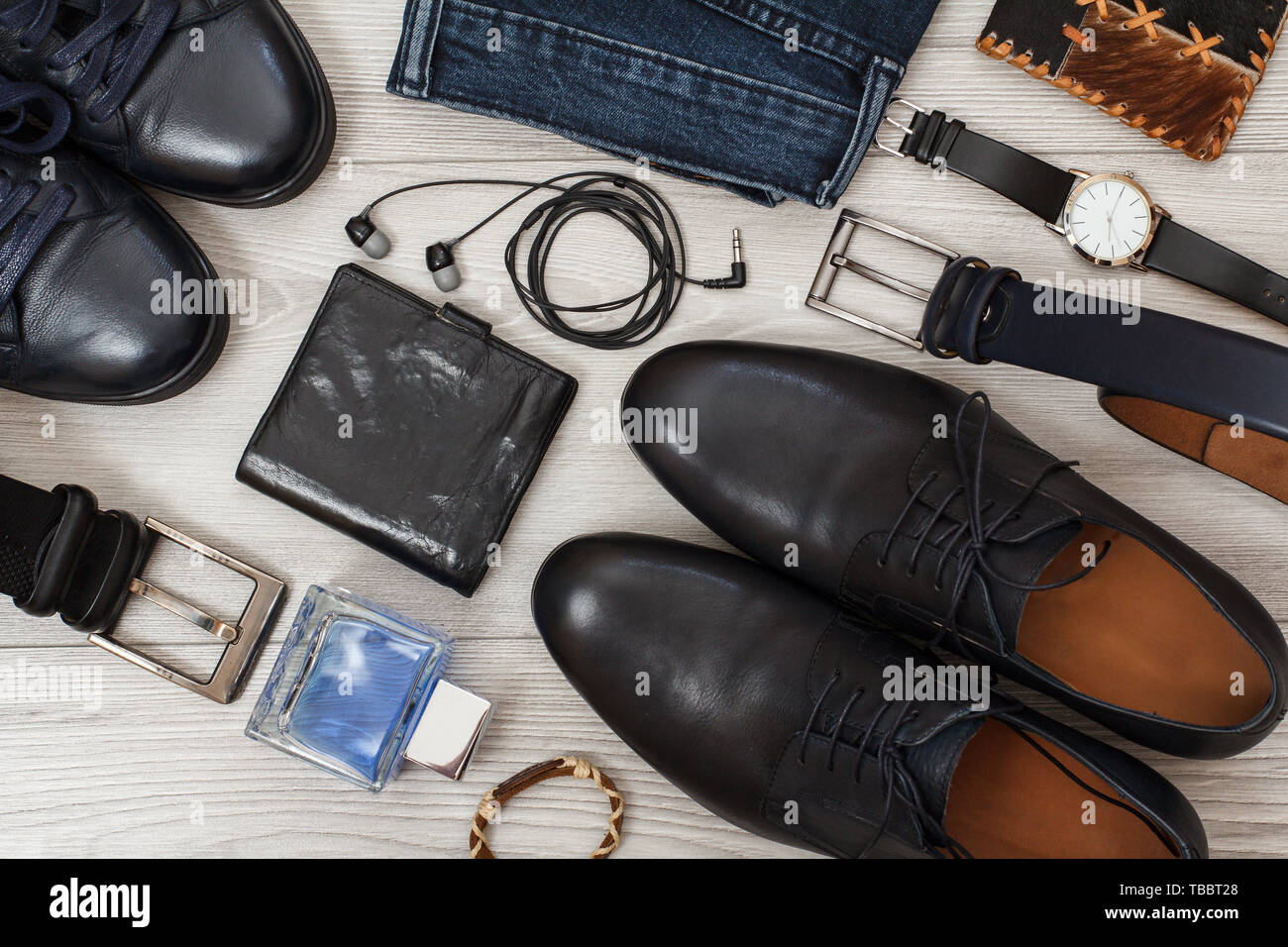 Zwei Paare von schwarzem Leder Männer Schuhe, Gürtel für Männer, Jeans,  Männer Köln, Armbanduhr, Kopfhörer und Geldbeutel auf grau Holzbretter.  Herren Zubehör Stockfotografie - Alamy