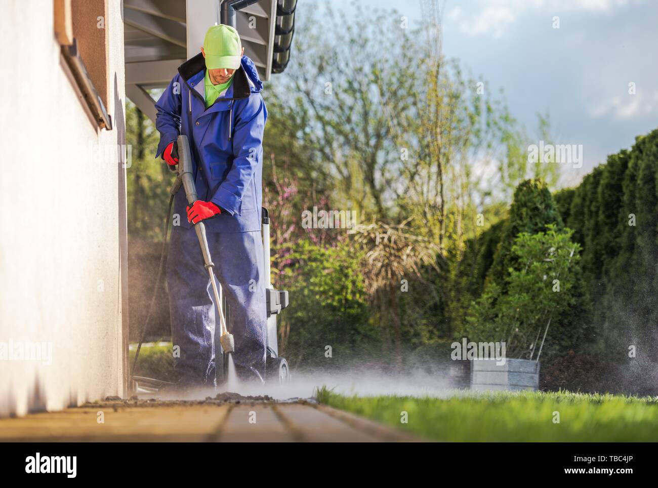 Reinigung Haus Hinterhof Brick Pfade mit Hochdruckreiniger. Kaukasische Männer und die Feder Wartung. Stockfoto