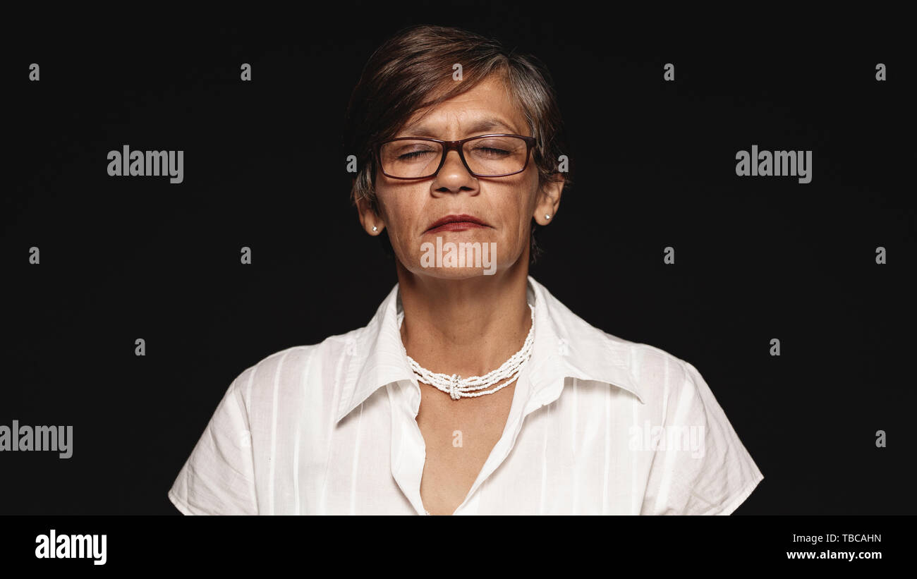Nahaufnahme der älteren Frau in Brillen mit geschlossenen Augen. Portrait der älteren Frau auf schwarzen Hintergrund isoliert. Stockfoto