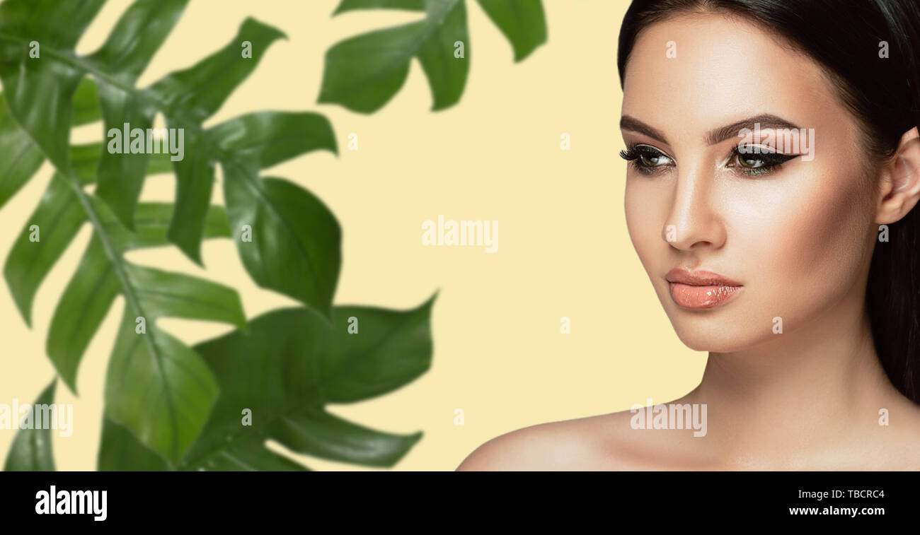 Schöne Frau Gesicht mit perfekten Make-up und gesunde Haut mit tropischen Blatt. beauty Gesichtspflege Stockfoto