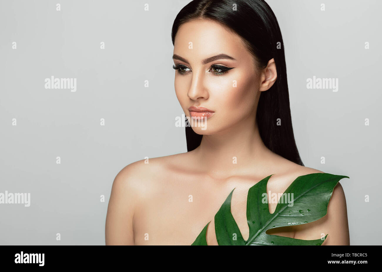 Schöne Frau Gesicht mit perfekten Make-up und gesunde Haut mit tropischen Blatt. beauty Gesichtspflege Stockfoto