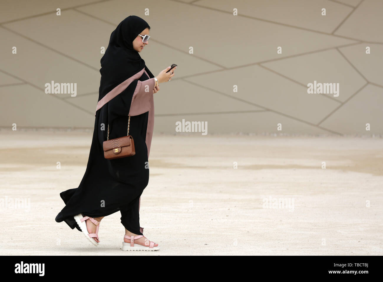 Doha, Katar - 11 April, 2019: Ein qatari Frau in einem langen schwarzen Kleid namens abayha Spaziergänge rund um die National Museum von Qatar. Stockfoto