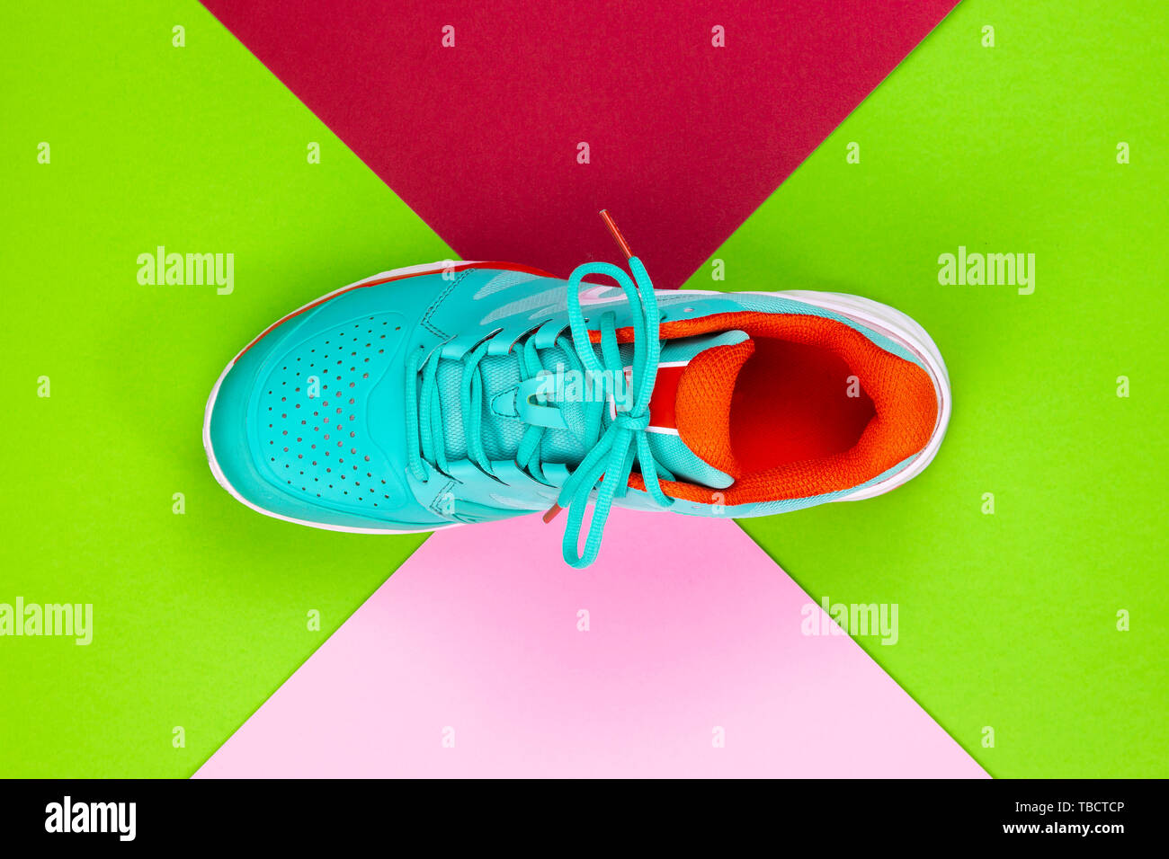Rot, Hellblau, Weiß neu Tennisschuh im Studio Schuß über Grün, Pink, Lila, Hintergrund. Direkt von oben. Stockfoto