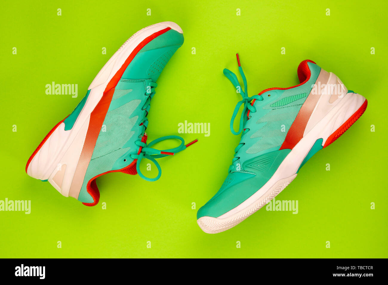 Rot, hellblau, weiß, Paar neue Tennisschuhe im Studio Schuß über grünen Hintergrund. Direkt von oben. Stockfoto