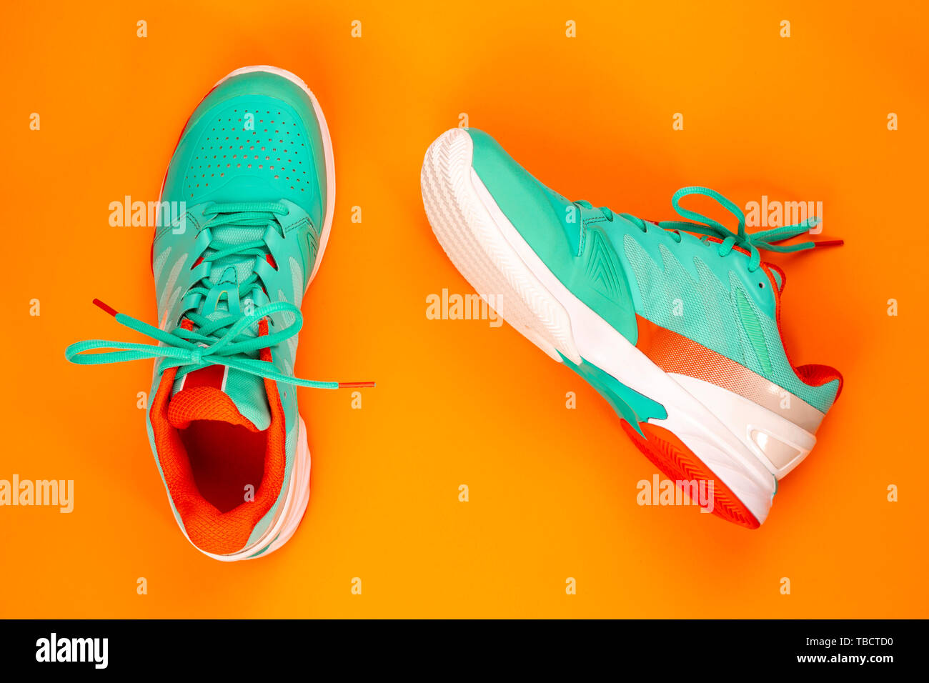 Rot, hellblau, weiß, Paar neue Tennisschuhe im Studio Schuß über orange hinterlegt. Direkt von oben. Stockfoto