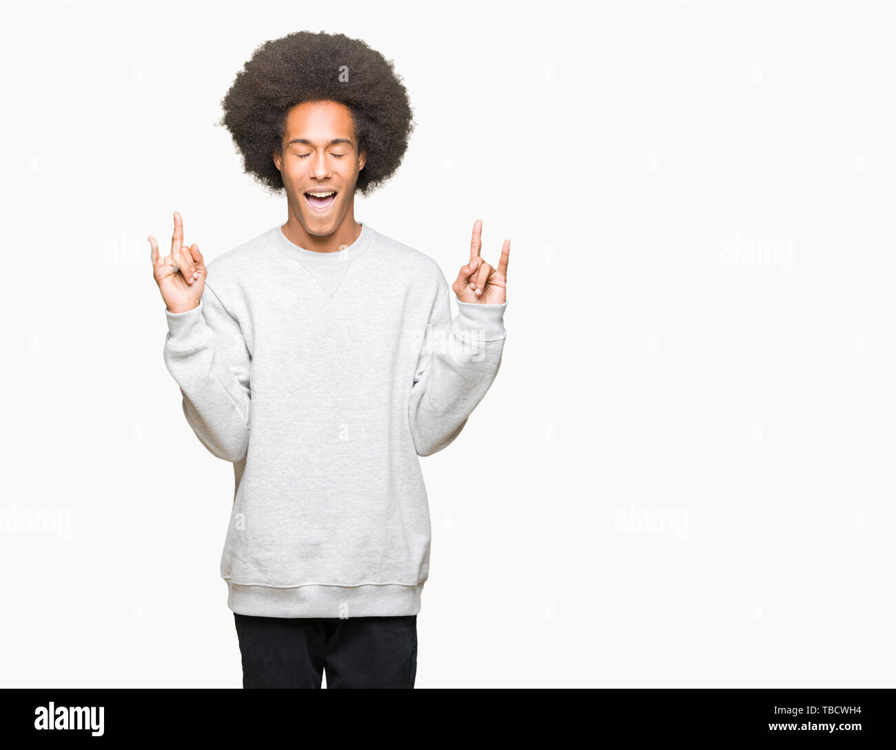 Junge afrikanische amerikanische Mann mit afro Haar zu tragen sportliche Sweatshirt schreien mit verrückten Ausdruck tun Rock Symbol mit hands up. Musik Star. Schwere Stockfoto