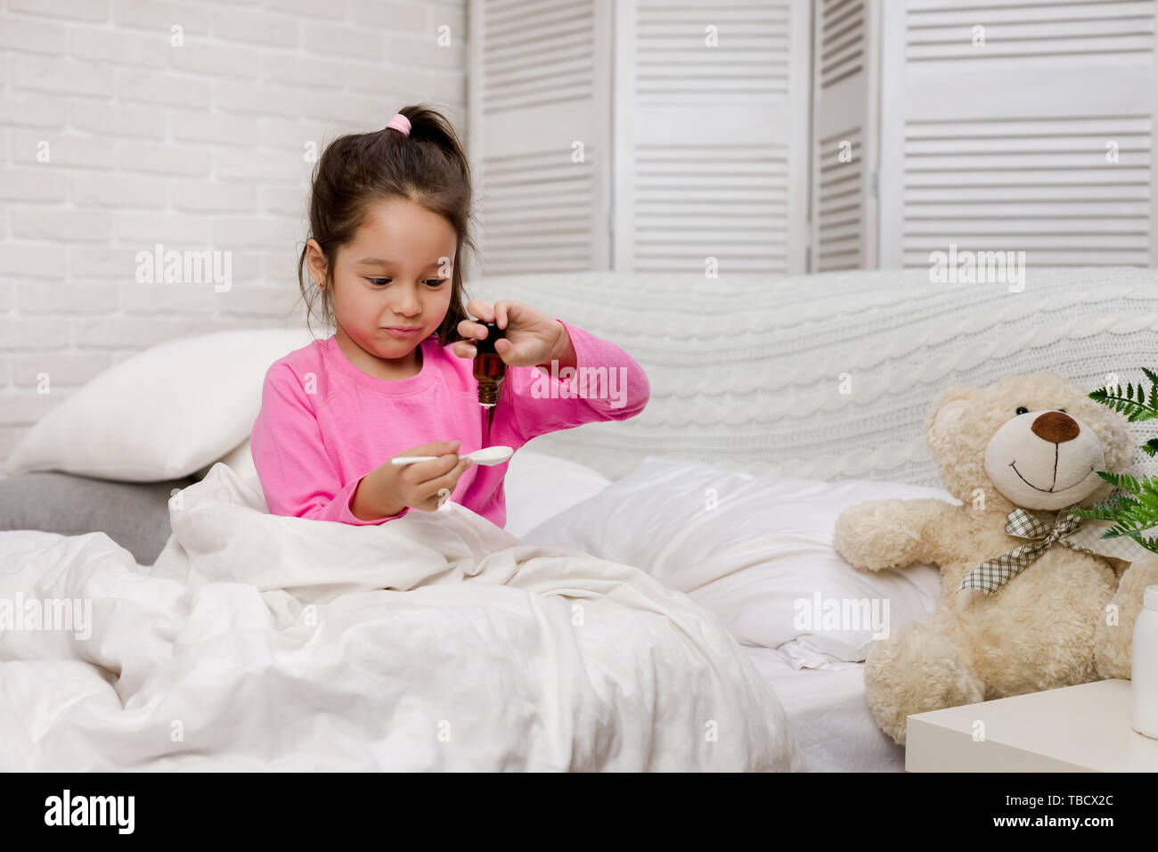 Kranken Kind Mädchen gießen antipyretische Sirup für Kind im Bett Stockfoto