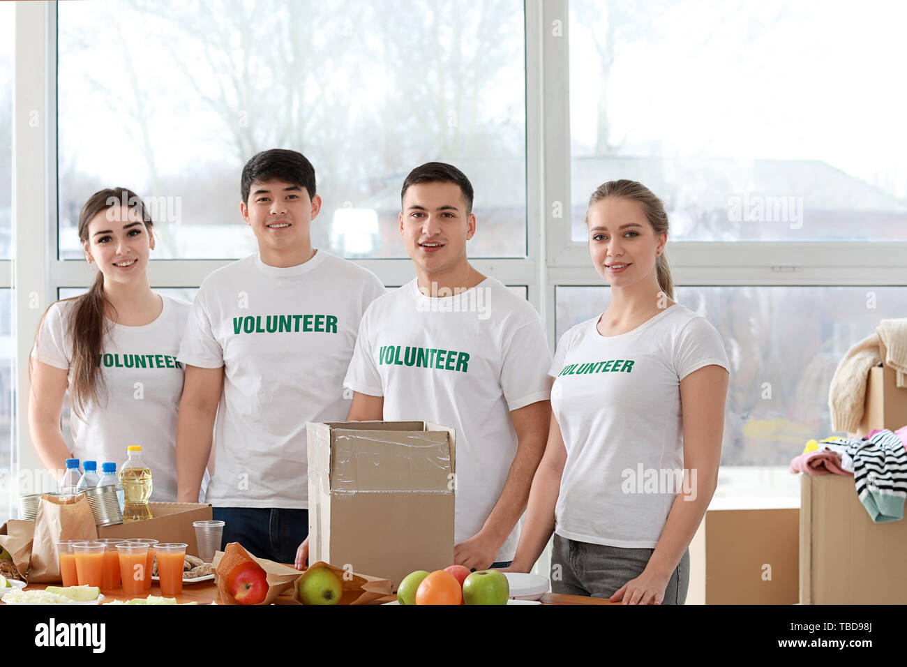 Die jungen Freiwilligen mit Lebensmitteln für arme Menschen in Innenräumen Stockfoto