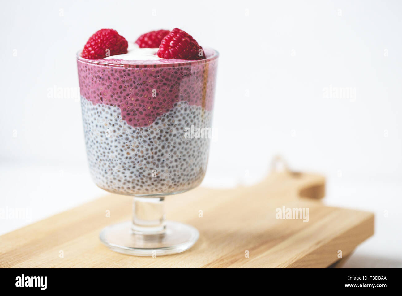 Chia Samen parfait Milchreis mit Mandeln Milch, Joghurt, pinkfarbenen Drachenfrucht pitaya Pulver und Himbeeren Dessert im Glas. Superfood und veganes Essen conce Stockfoto
