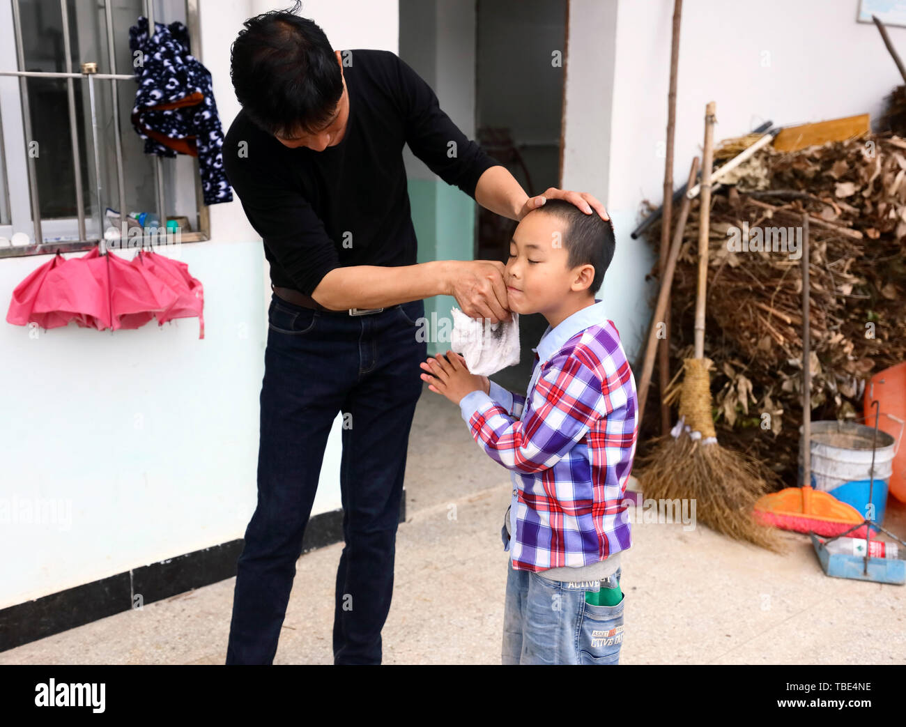 (190601) - Peking, 1. Juni 2019 (Xinhua) - Wang Beihai (L) reinigt Gesicht von Chen Weiyu vor dem Abendessen an der Volksschule in Sanhe Dabaidi Township von ruijin Stadt, der ostchinesischen Provinz Jiangxi, 7. Mai 2019. Das Sanhe Volksschule, tief in den Bergen von Ruijin befindet, hat nur einen Lehrer, 46-jährige Wang Beihai, und ein Student Chen Weiyu, ein 9-jähriger Junge aus einer armen Familie. Der student Chen Weiyu, der mit seinem grandapa, verwendet, um an einer Schule etwa 20 Kilometer von seinem Haus zu stude lebte. Sein Großvater hatte ihm zu und von der Schule in die durch Fahren des Traktors: nehmen Sie die e Stockfoto
