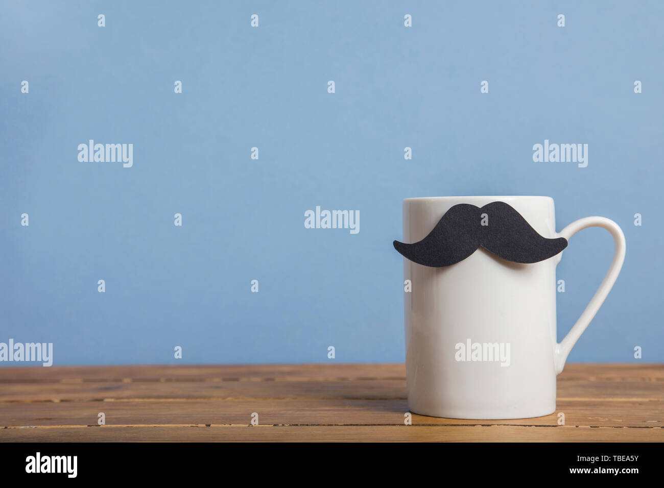 Vatertag Kaffeebecher mit einem Papier Schnurrbart vor einem blauen Hintergrund Stockfoto