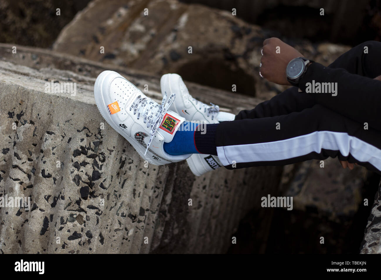 Kapstadt, Südafrika. 01. Juni 2019. Ein paar weiße Nike Air Force 1 tun Sie es einfach abgenutzt Pack von einem Mann sitzen auf konkrete Bausteine. Stockfoto