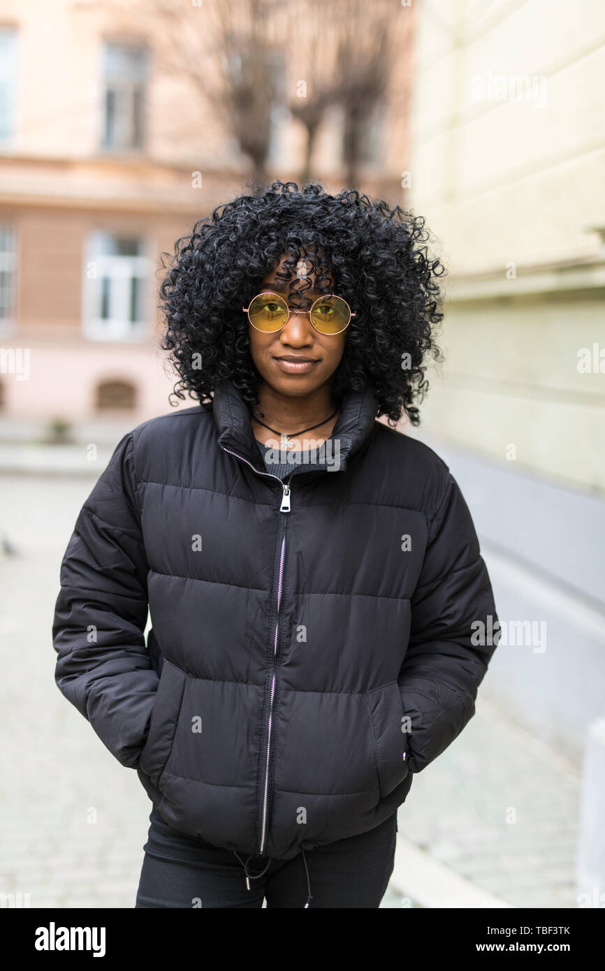 Fröhliche junge afrikanische Frau mit Mantel wandern im Freien Stockfoto