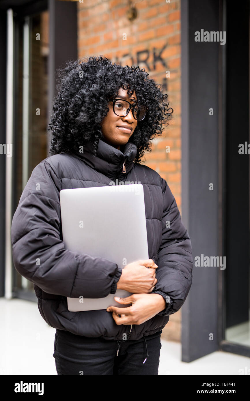 Junge Frau, die auf der Straße arbeiten, die auf Notebook- und Gespräch am Handy. Stockfoto