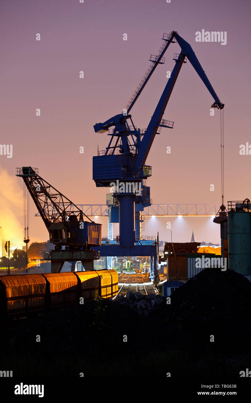 Nacht Blick auf Eisenbahnschienen, einem Bahnhof und einem großen Kran in einer Kohle Hafen. Stockfoto